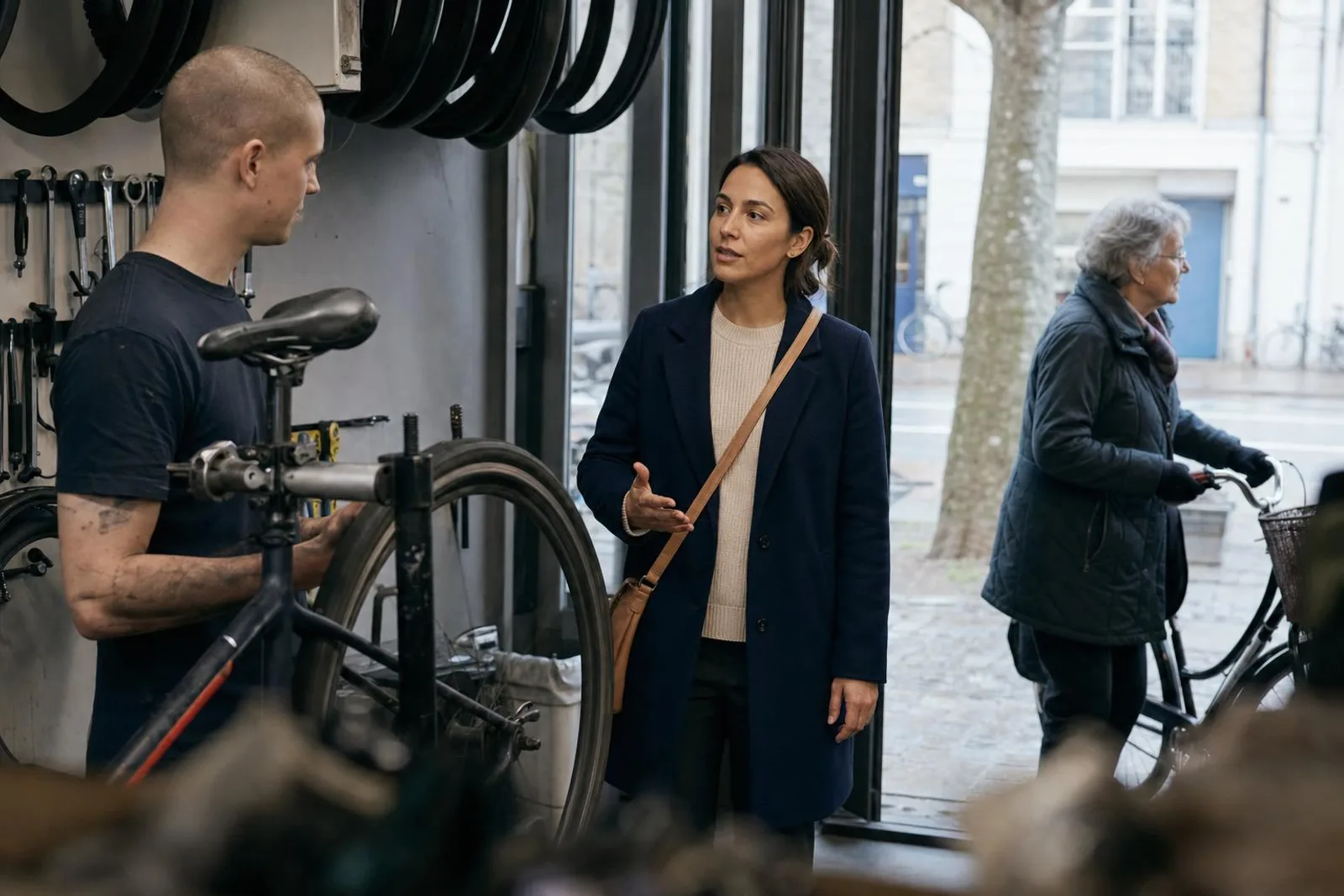 Dans un atelier de réparation de vélos, une passante converse avec le mécanicien.