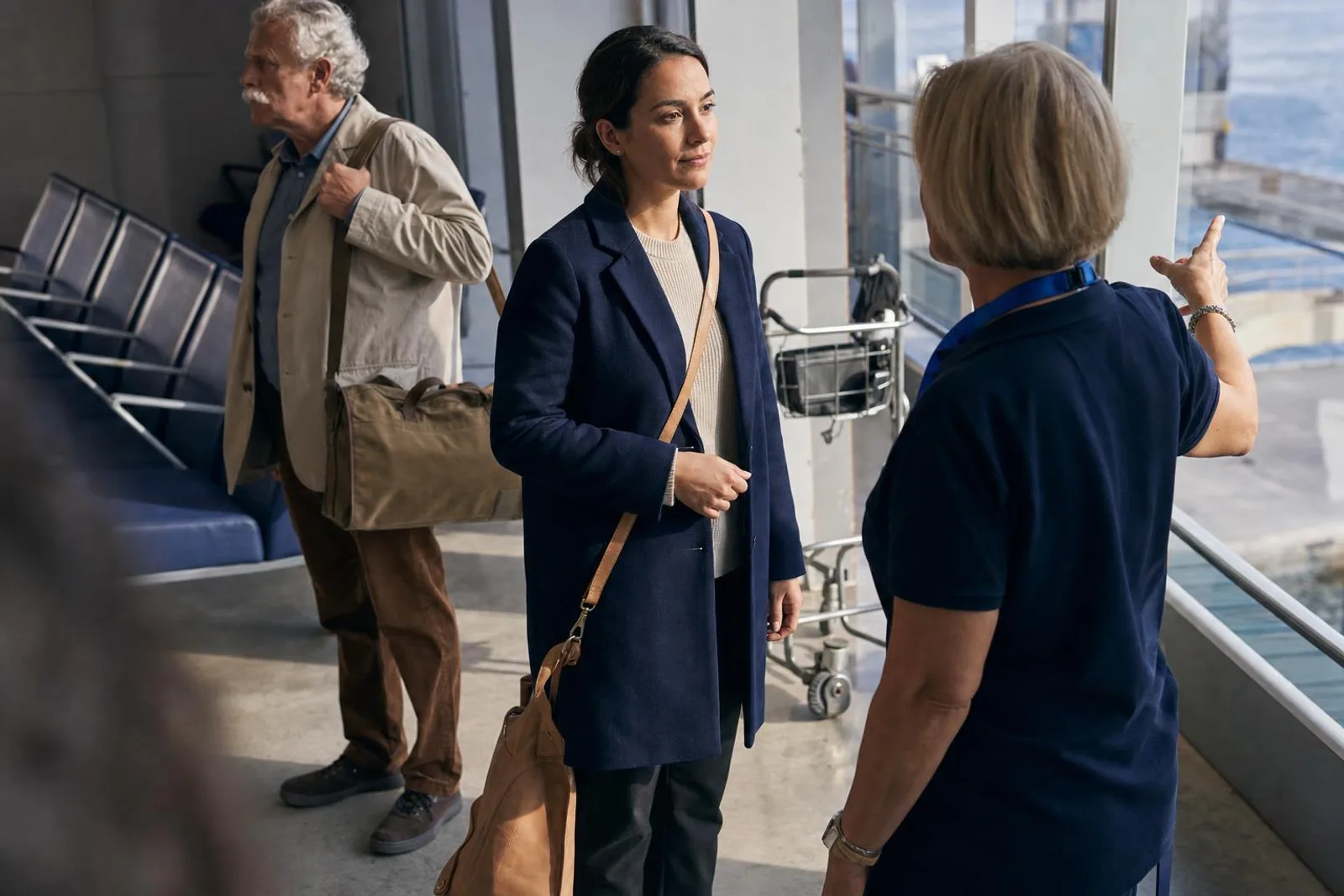 Dans le hall d'un terminal de ferries, une voyageuse échange avec une agente en uniforme.